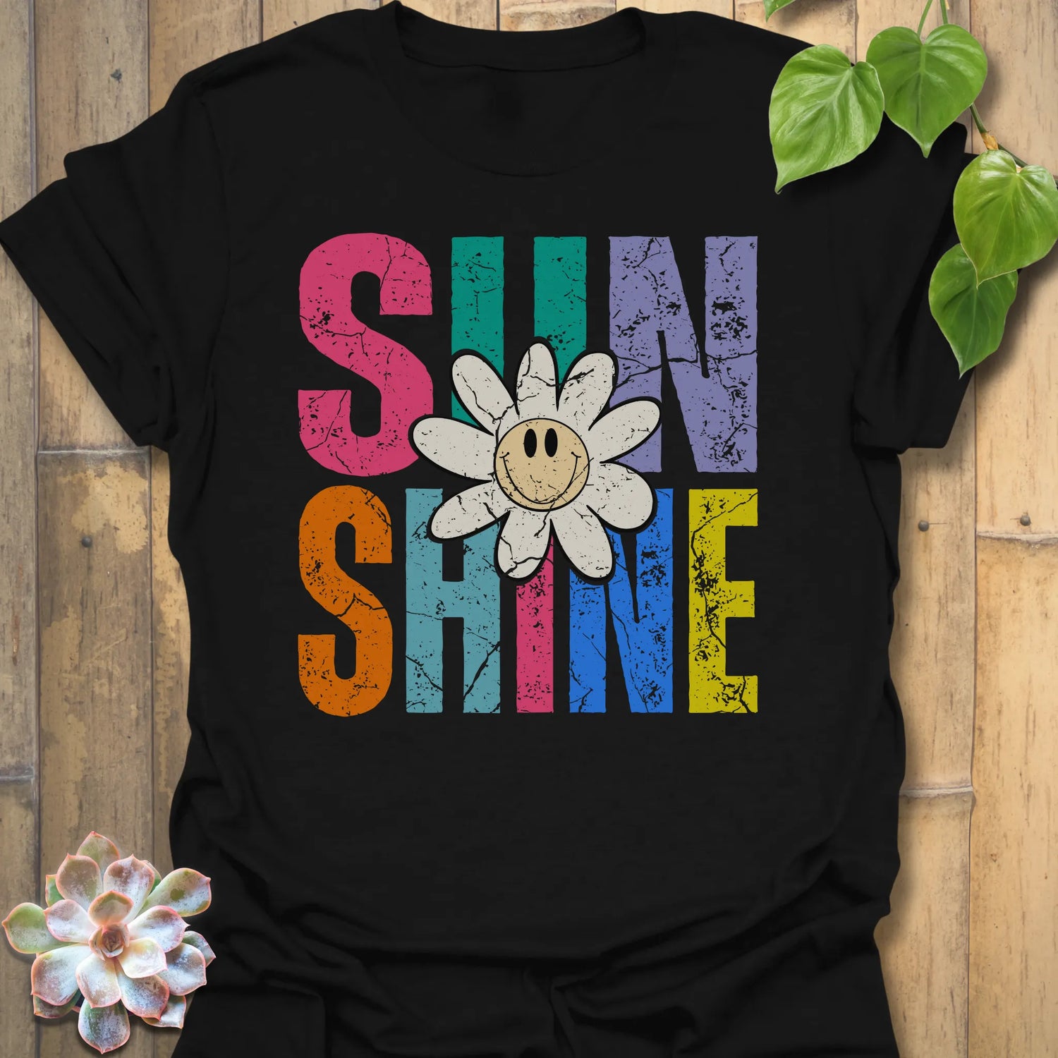 Black t-shirt featuring the design Sunshine printed in bold colorful letters, funny sunflower casual summer shirt.