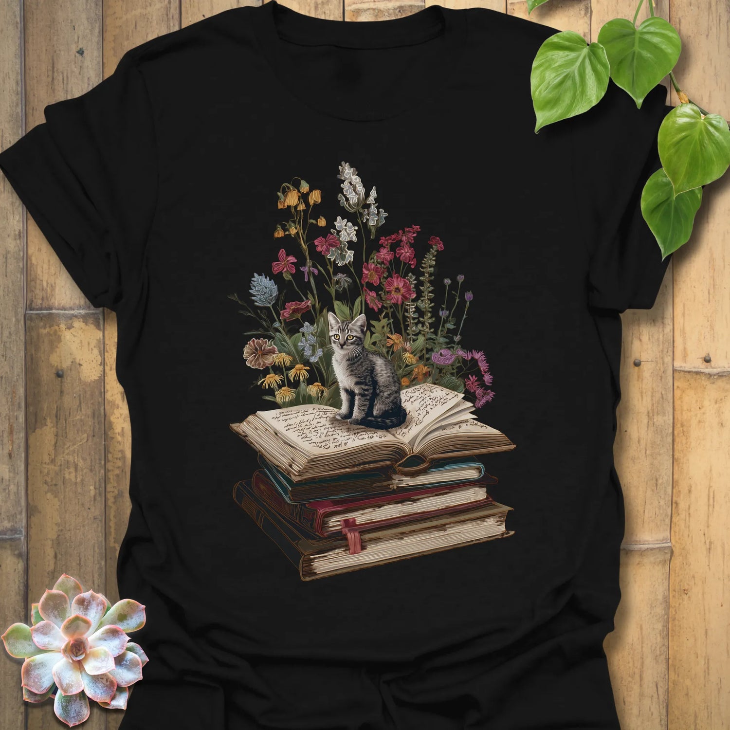 Black t-shirt featuring the design Whiskers &amp; Words printed in books and cats with flowers, cat lover reading shirt.
