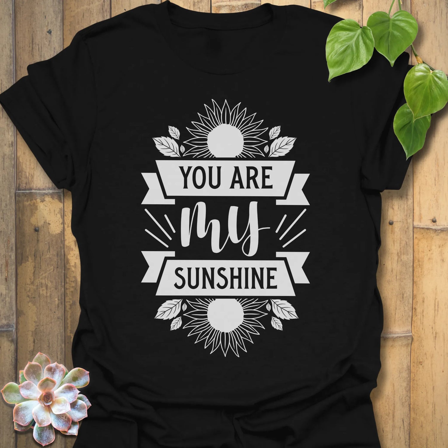 Black t-shirt featuring the design You Are My Sunshine printed in bold letters, nature-inspired graphic tee.