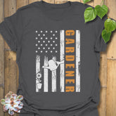 Charcoal gardening t-shirt featuring the design Gardener with a vertical word, American flag, plant, and watering sprinkler print, perfect for garden lovers