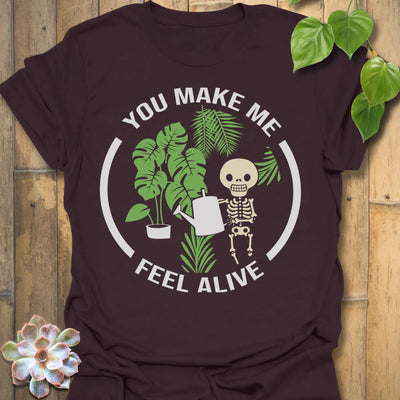 Dark Chocolate t-shirt featuring the design Feel Alive printed in bold white letters with plants, motivational graphic tee.
