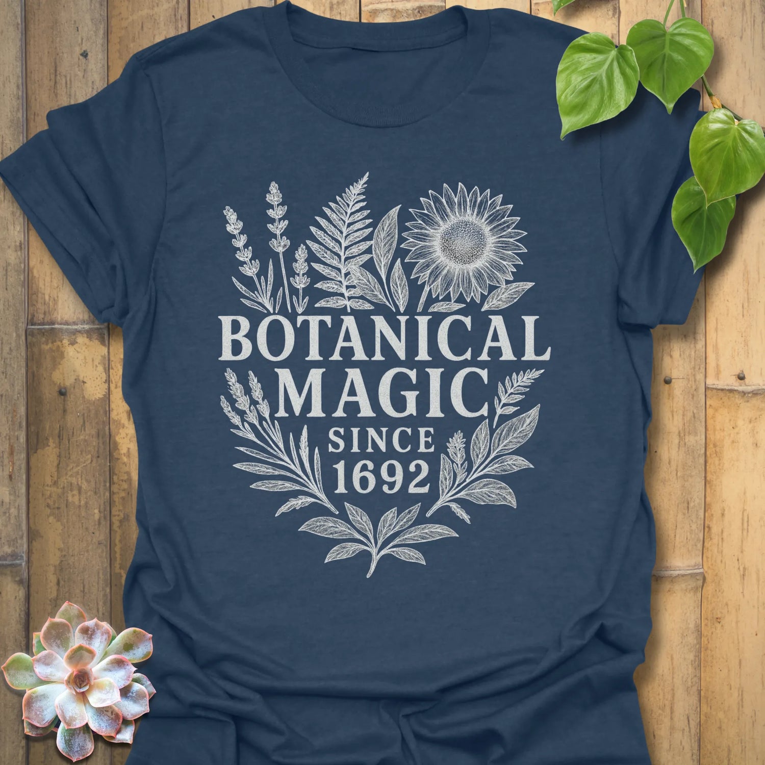 Heather Navy t-shirt featuring the design Botanical Magic printed in bold letters, floral graphic tee.