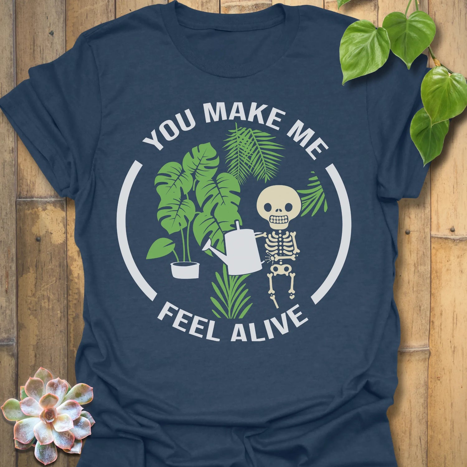 Heather Navy t-shirt featuring the design Feel Alive printed in bold white letters with plants, motivational graphic tee.