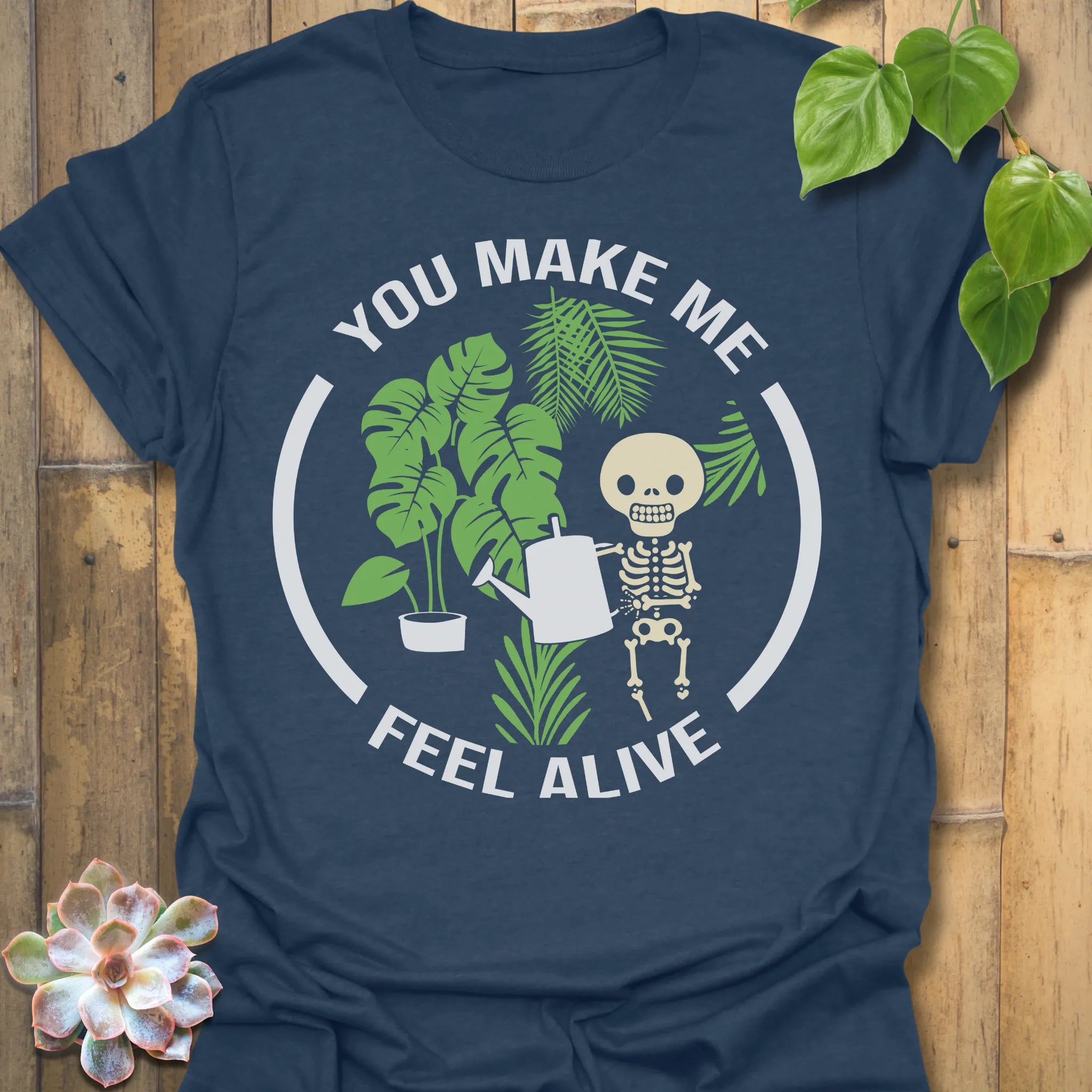 Heather Navy t-shirt featuring the design Feel Alive printed in bold white letters with plants, motivational graphic tee.