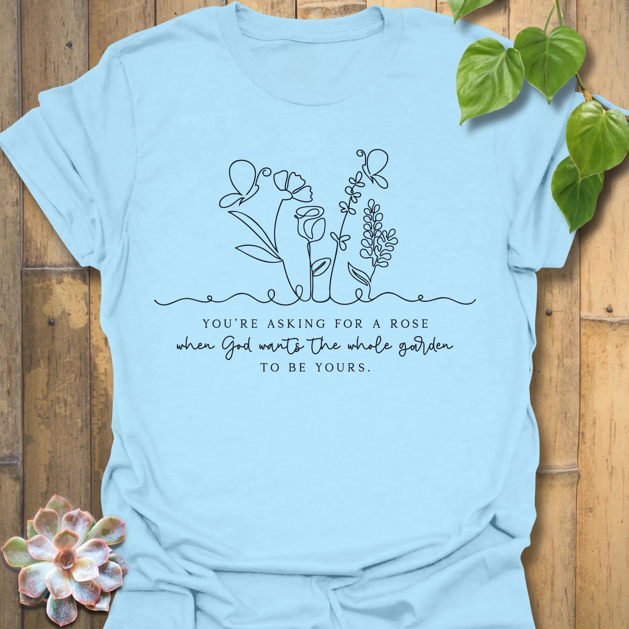Light Blue t-shirt featuring the design Asking For A Rose printed in black letters and flowers, floral humour shirt.