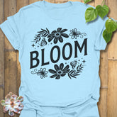 Light Blue t-shirt featuring the design Bloom printed in bold black letters, floral graphic tee for plant lovers.