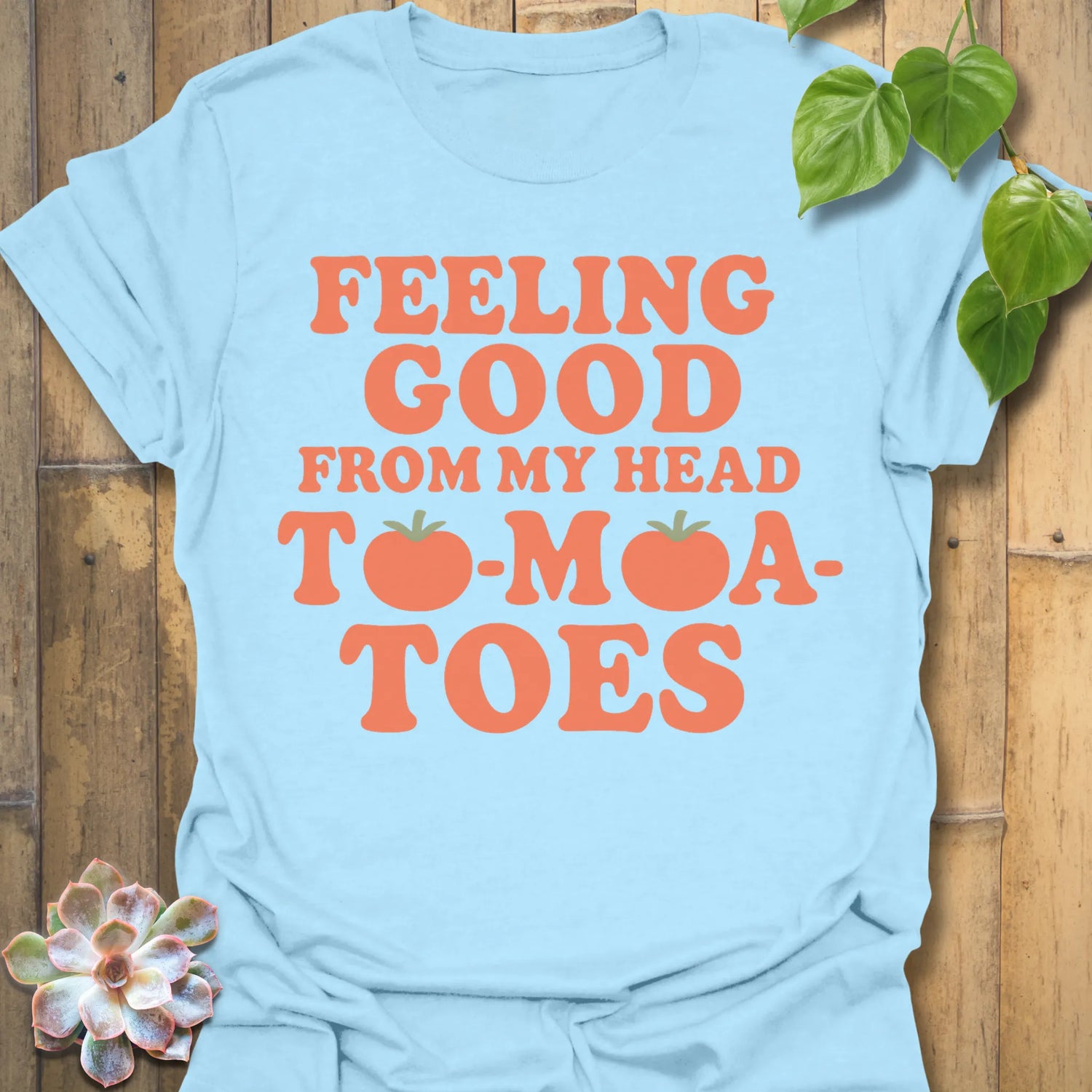 Light Blue t-shirt featuring the design Feeling Good printed in bold orange letters, feel-good graphic shirt.