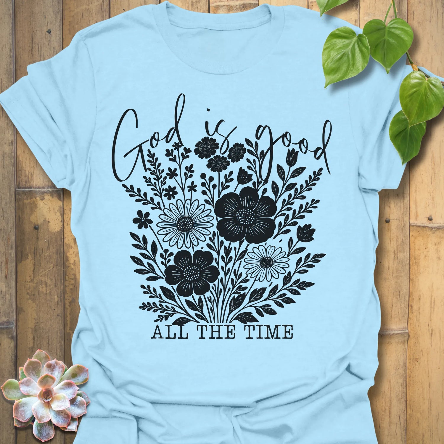 Light Blue t-shirt featuring the design God Is Good printed in black letters, religious faith shirt.