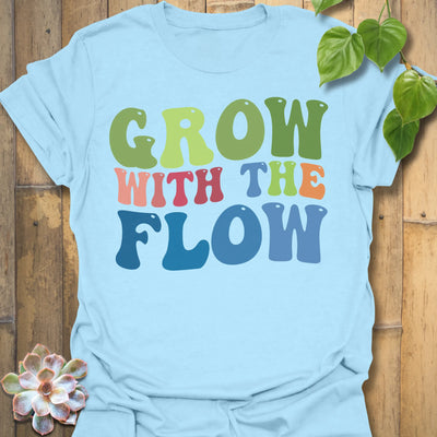 Light Blue t-shirt featuring the design Grow With The Flow printed in bold colorful letters, mindful garden shirt.
