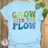 Light Blue t-shirt featuring the design Grow With The Flow printed in bold colorful letters, mindful garden shirt.