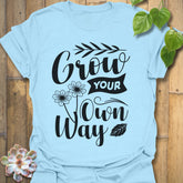 Light Blue t-shirt featuring the design Grow Your Own Way printed in bold black letters, positive garden shirt