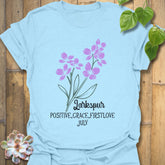 Light Blue t-shirt featuring the design July Larkspur with a soft larkspur flower graphic, making it a stylish floral print tee for garden-inspired fashion and summer outfits.