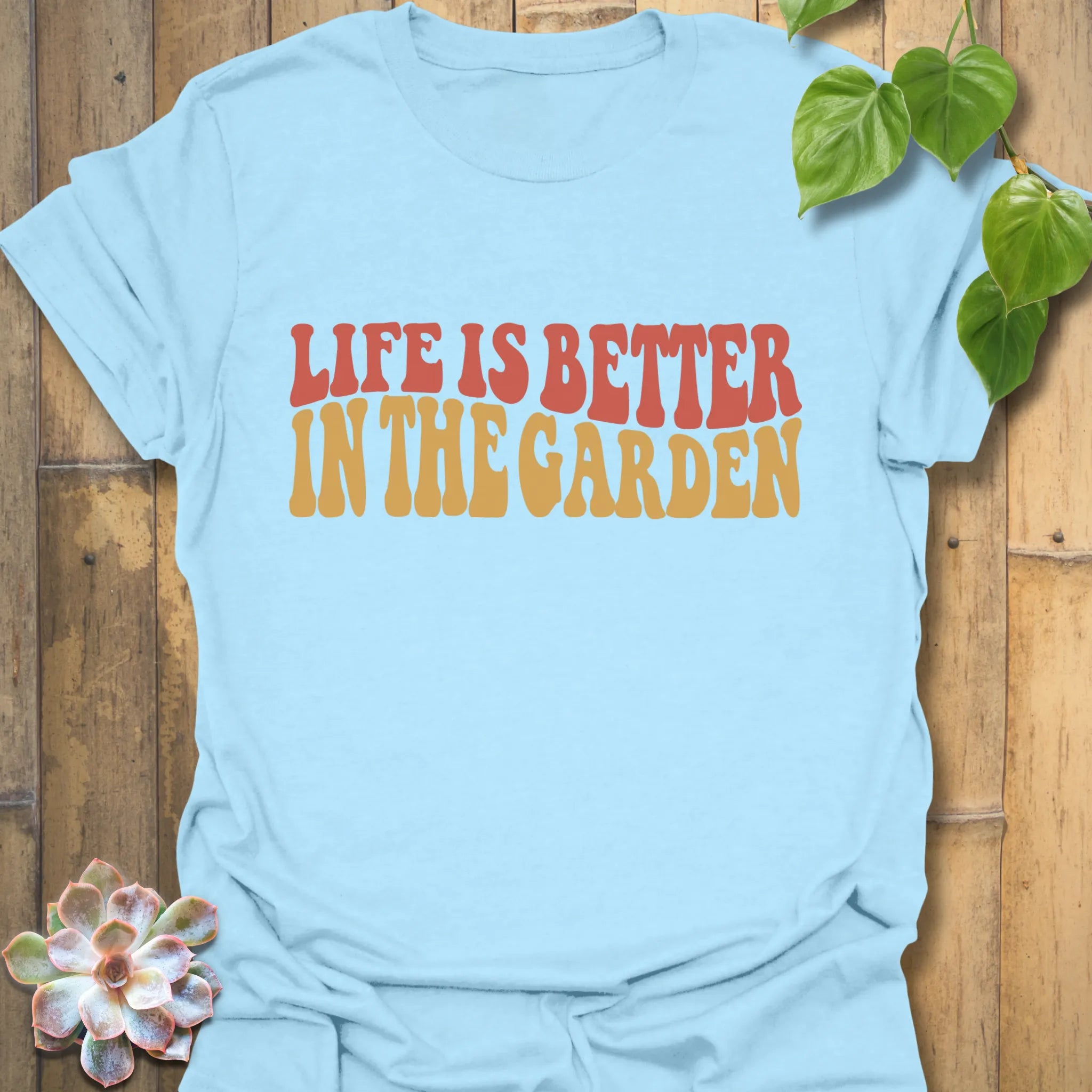 Light Blue t-shirt featuring the design Life is better in the garden printed in green floral lettering, nature-inspired garden lover shirt
