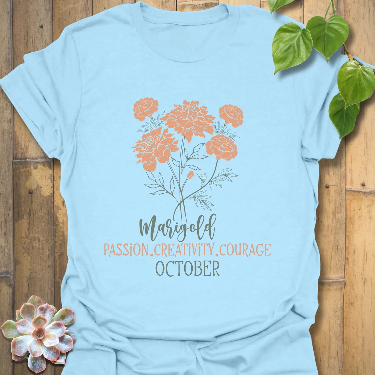 Light Blue t-shirt featuring the design October Marigold printed with a bright marigold flower, a stylish nature-inspired floral tee.