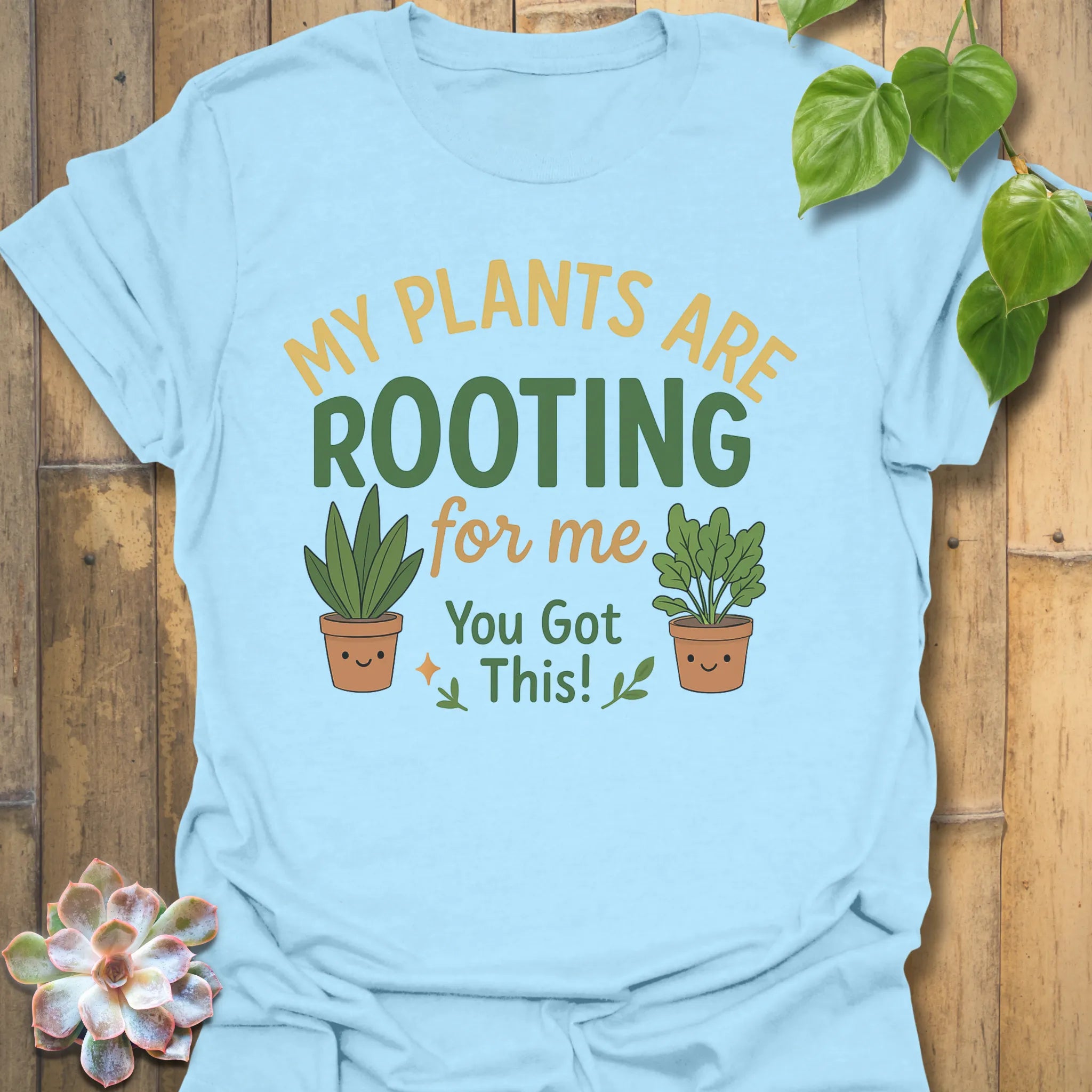 Light Blue t-shirt featuring the design Plants Are Rooting printed in bold letters, gardening graphic tee.