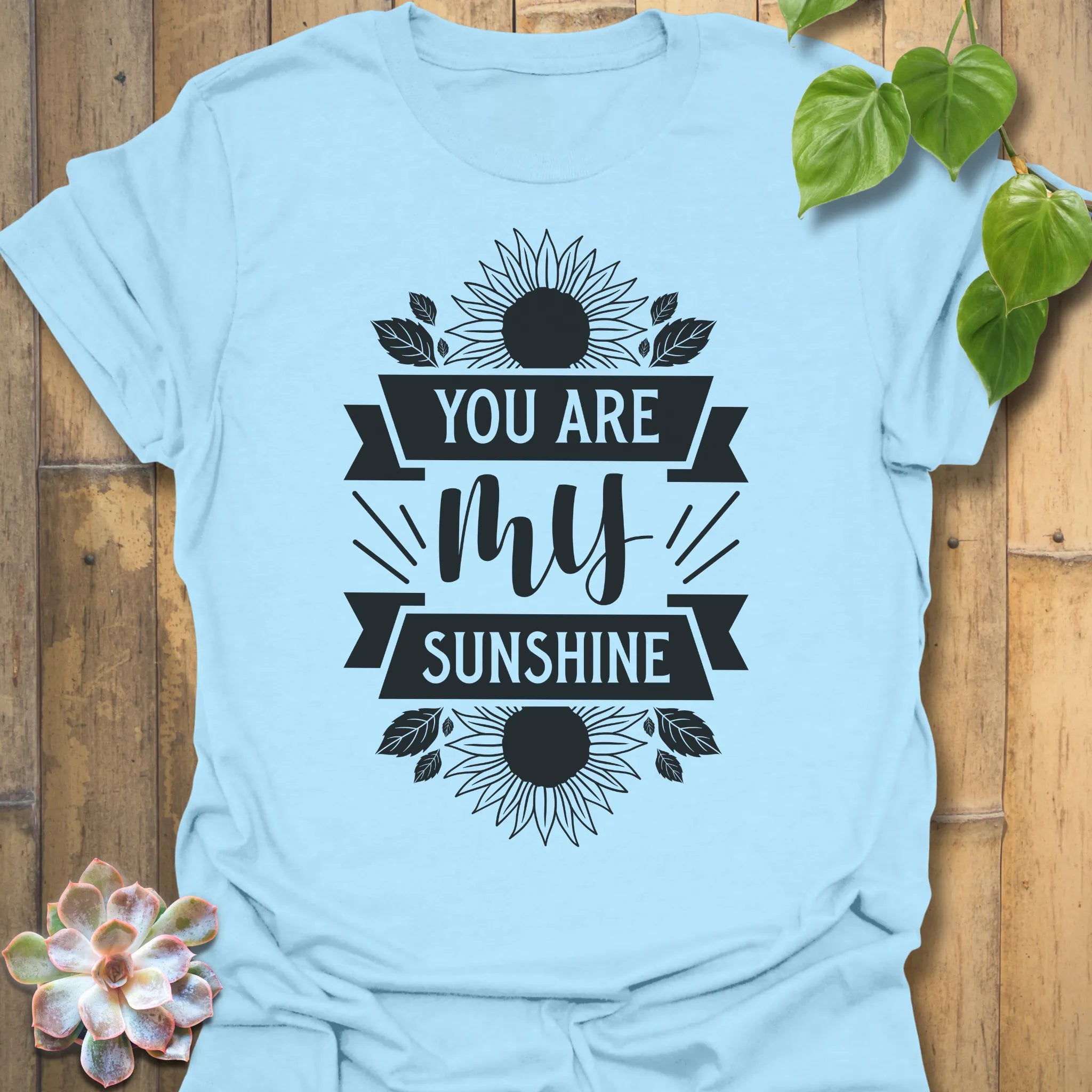 Light Blue t-shirt featuring the design You Are My Sunshine printed in bold letters, nature-inspired graphic tee.