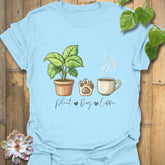 Light Blue t-shirt with “Plant, Dog, Coffee” lettering – soft casual shirt for coffee lovers and plant enthusiasts.