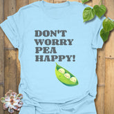 Light blue t-shirt featuring the design “Don’t Worry Pea Happy” in bold white letters with three smiling peas in a pod illustration