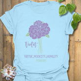 Light blue t-shirt featuring the design February Violet with a rose flower print, a soft pastel floral graphic t-shirt for women and men.
