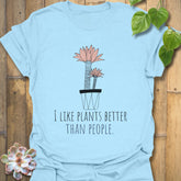 Light blue t-shirt featuring the text “I like plants better than people” with a flower in a pot artwork
