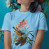 Light blue t-shirt with the Spring Songbirds illustration of two birds surrounded by soft pink flowers and leaves.