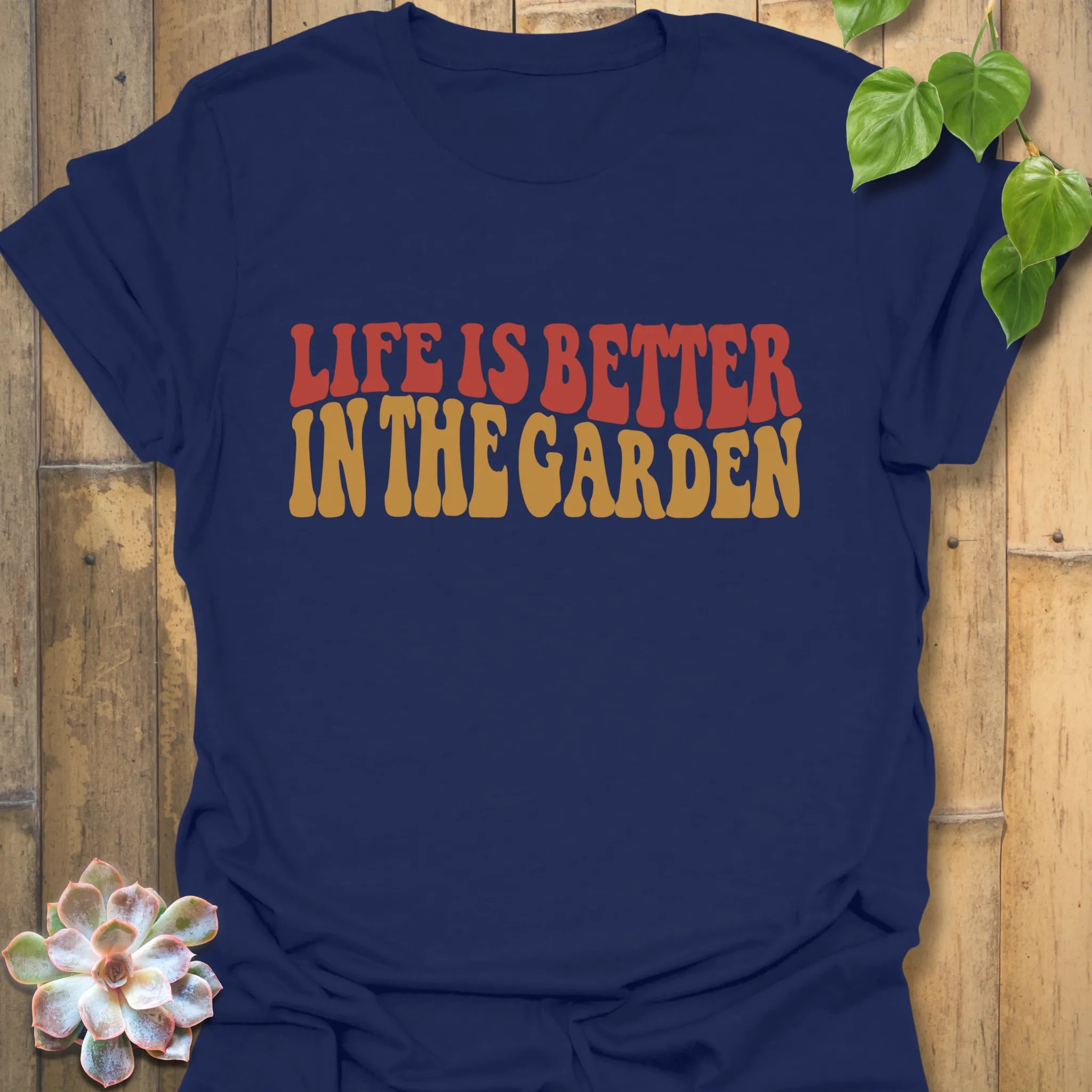Navy t-shirt featuring the design Life is better in the garden printed in green floral lettering, stylish gardening shirt for plant enthusiasts