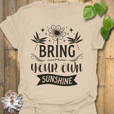Sand t-shirt featuring the design Bring Your Own Sunshine printed in bold black letters, positive vibes shirt.