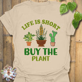 Sand t-shirt featuring the design Buy The Plant printed in bold letters, funny gardening shirt.