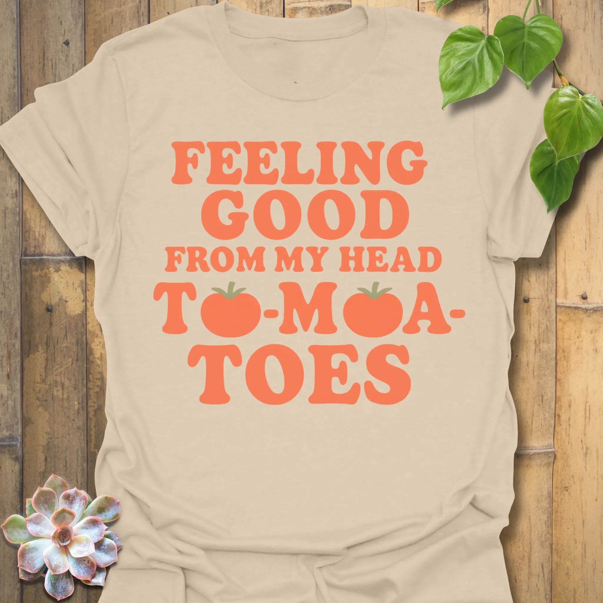 Sand t-shirt featuring the design Feeling Good printed in bold orange letters, feel-good graphic shirt.