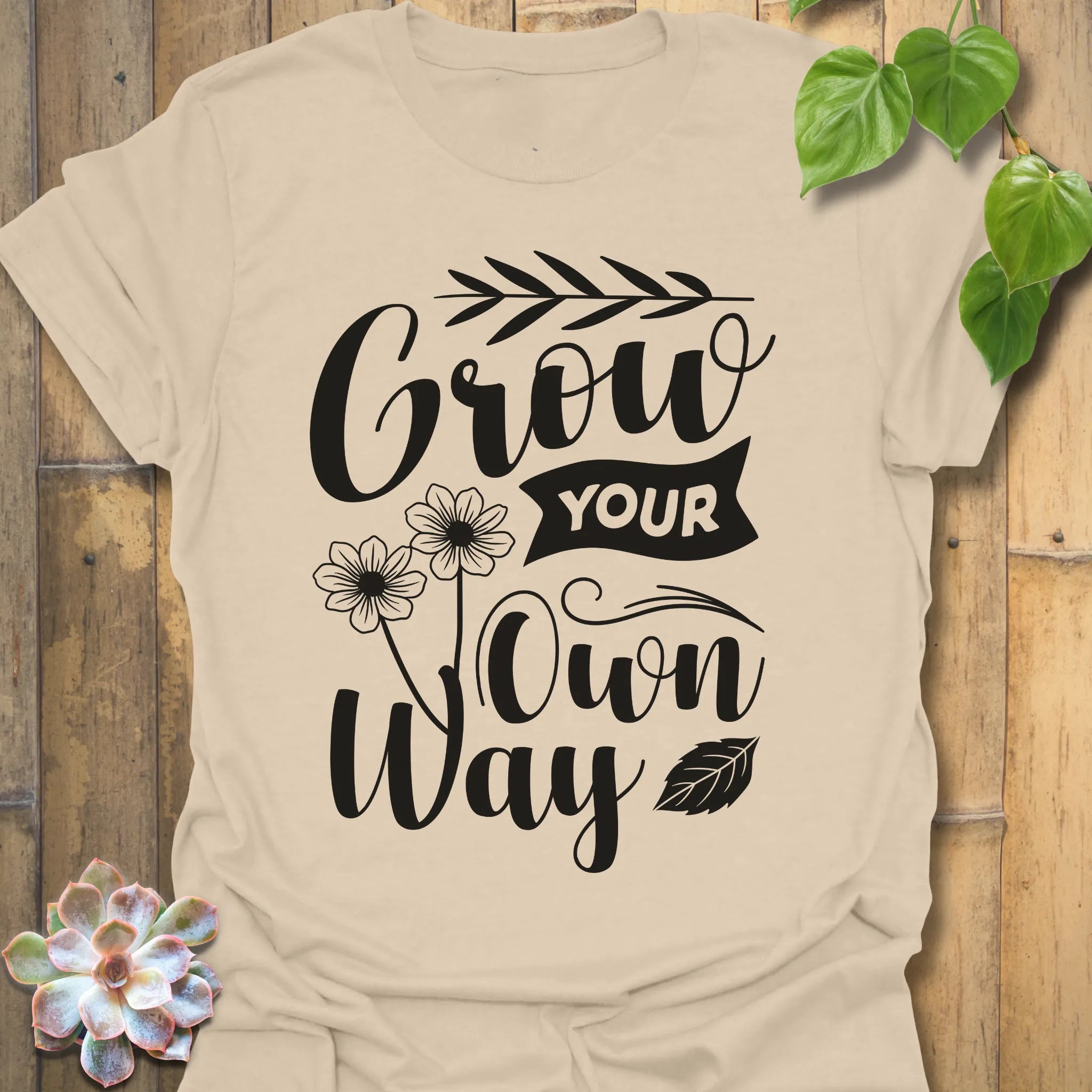 Sand t-shirt featuring the design Grow Your Own Way printed in bold black letters, positive garden shirt