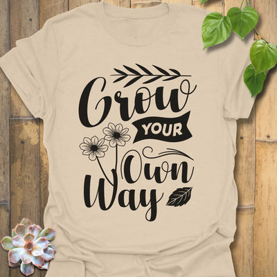 Sand t-shirt featuring the design Grow Your Own Way printed in bold black letters, positive garden shirt