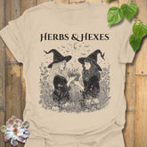 Sand t-shirt featuring the design Herbs & Hexes printed in bold black letters, botanical witch t-shirt.