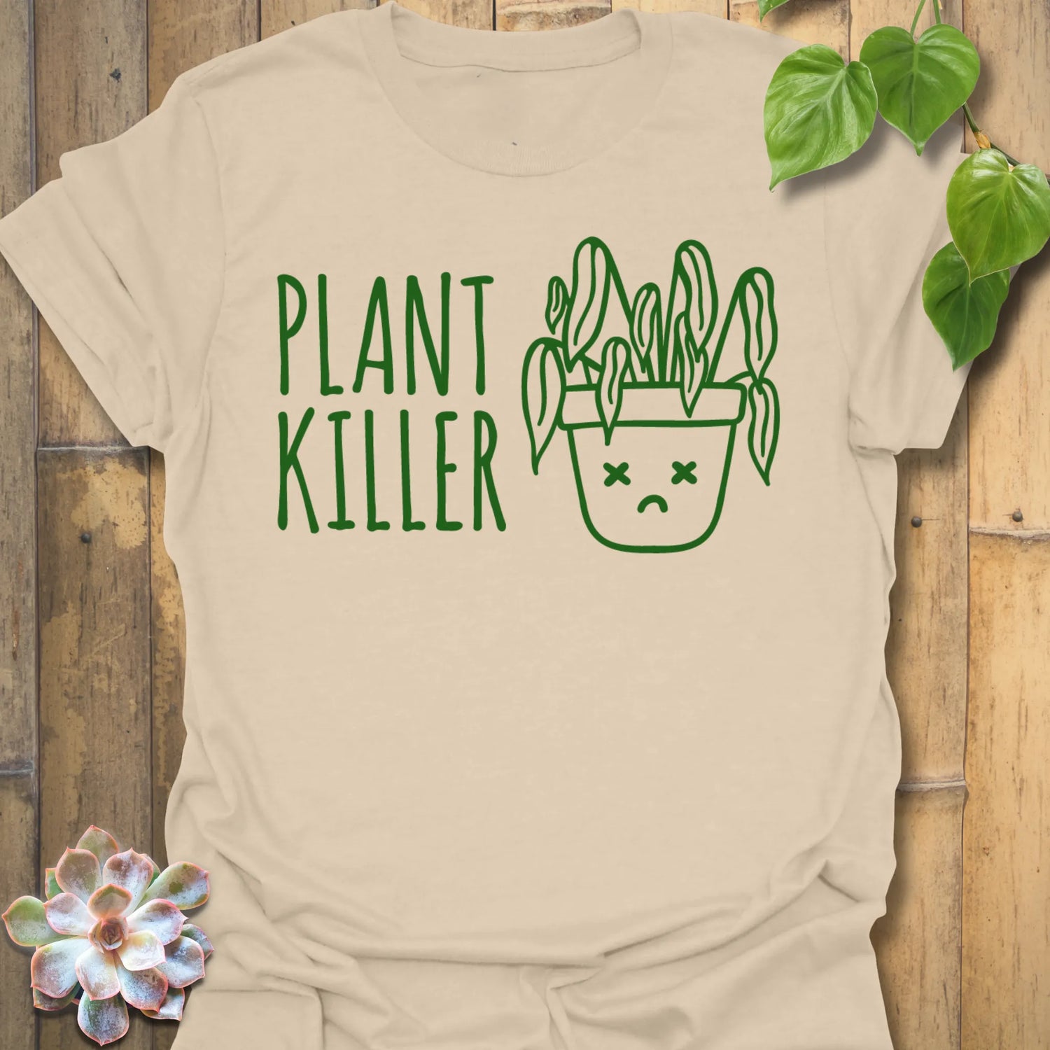 Sand t-shirt featuring the design Plant Killer printed in bold green letters, funny plant lover shirt.