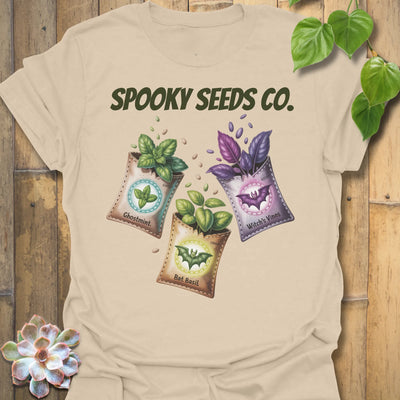 Sand t-shirt featuring the design Spooky Seeds Co. printed in bold letters, spooky plant lover shirt.