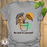 Sport grey t-shirt displaying the “Be-leaf in yourself” design with a plant in a pot
