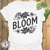 White t-shirt featuring the design Bloom printed in bold black letters, floral graphic tee for plant lovers.