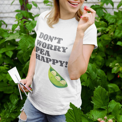 White t-shirt featuring the design “Don’t Worry Pea Happy” in bold green letters with three smiling peas in a pod illustration
