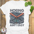 White t-shirt featuring the design Hoeing Ain’t Easy, funny gardening shirt.